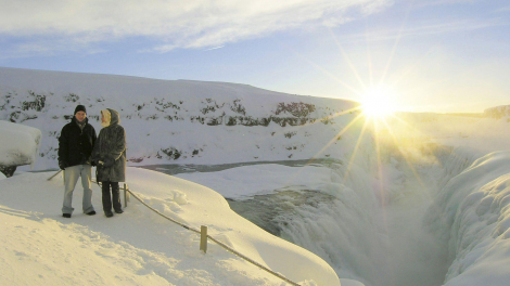 A couple posing in front of Icelandic landscapes and low winter sun